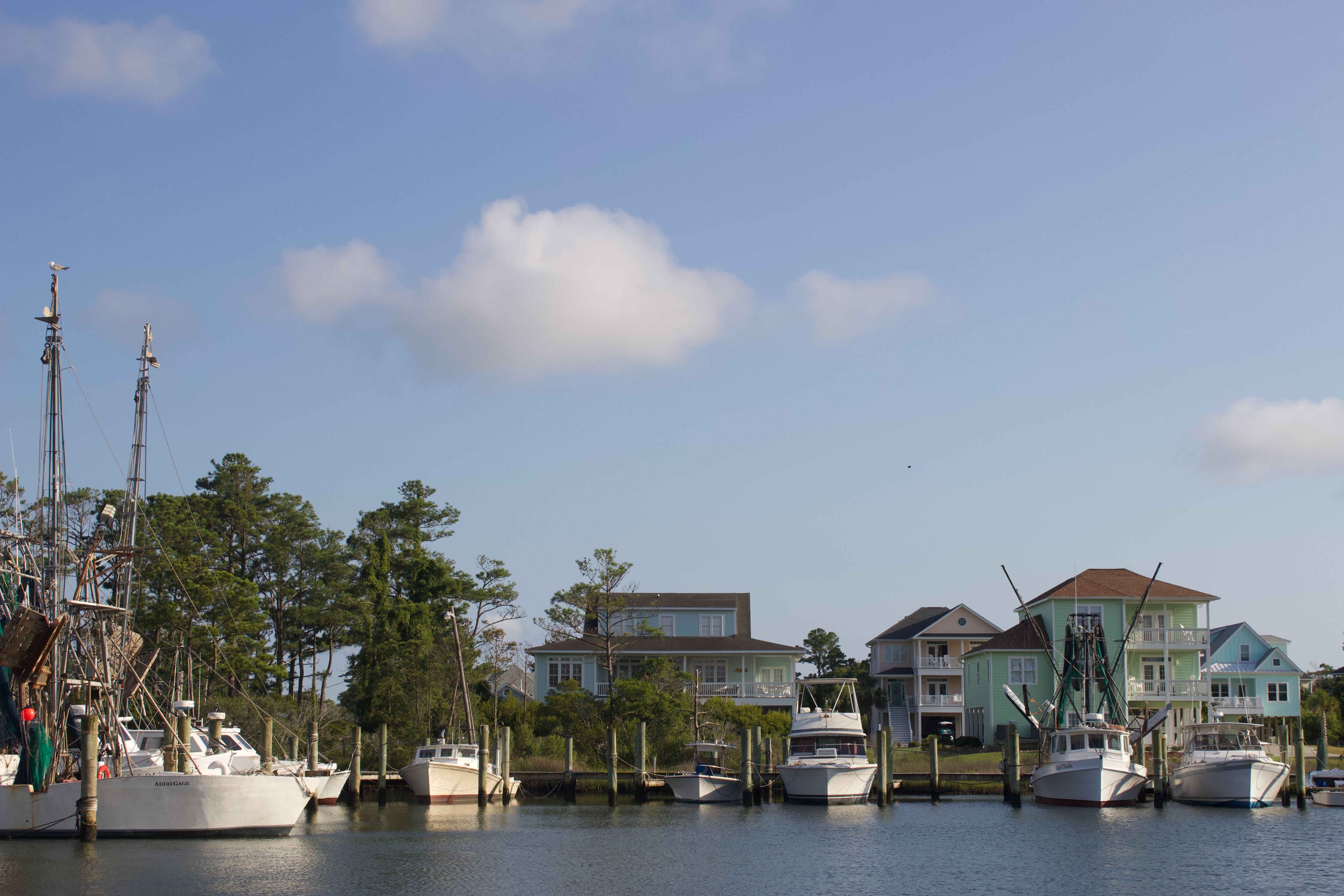 A commercial fishing harbor with large colorful beach homes in the background.